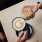 two people's hands with coffee drinks over a wooden table