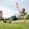 a young man stretches in the grass outdoors